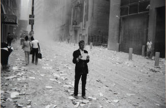 [Man reads a piece of paper in ashen street]