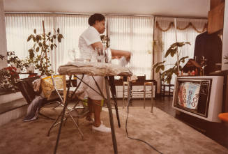 Untitled [woman ironing and watching TV]